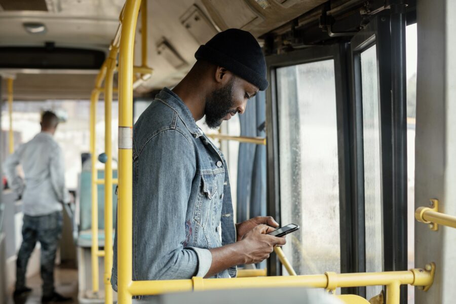 homem parado na porta de um ônibus com celular na mão